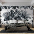 Modern black and white Monstera leaf wallpaper creating a stunning accent wall in a bright, minimal living room setting