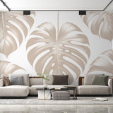 Monstera leaf wallpaper creating an elegant atmosphere in a modern living room with natural light highlighting the beige pattern