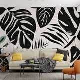 Modern black and white Monstera leaf wallpaper creating a bold statement in a minimalist living room setting