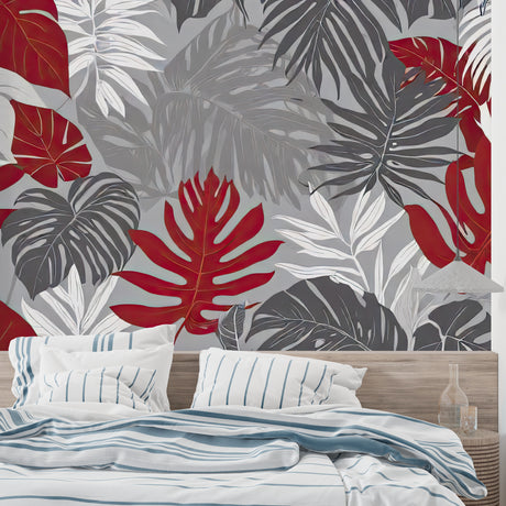 Red and grey Monstera leaf wallpaper in modern living room with grey sofa and natural light