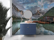 Mountain lake wallpaper creating depth in a modern living room, reflecting natural light with misty peaks and boathouse scene