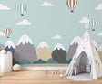 Mountain and hot air balloon wallpaper in a bright modern nursery with white furniture
