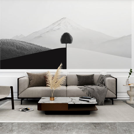 Minimalist mountain wallpaper with black tree silhouette creating drama in a modern living room setting