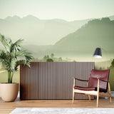 Misty forest mural wallpaper in a cozy bedroom setting with wooden furniture