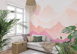 Watercolor mountain mural in a cozy bedroom setting with soft pink sunset tones