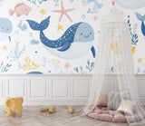 Kids bedroom transformed with marine life wallpaper featuring friendly whales and colorful fish