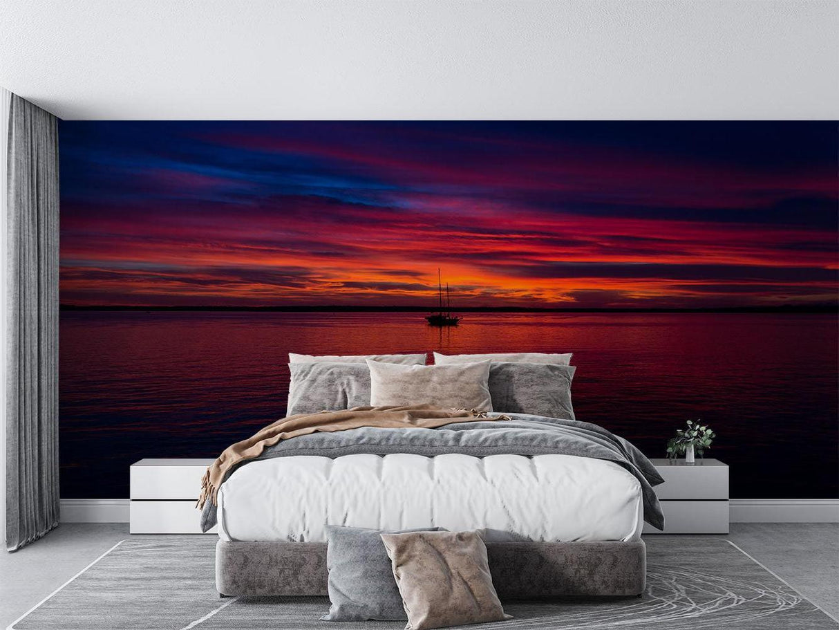 Dramatic red sunset seascape wallpaper as a stunning backdrop in a master bedroom suite