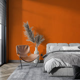 Solid orange wall mural in bedroom creating cozy atmosphere