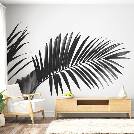 Black and white palm leaf mural wallpaper creating a bold statement in a bright modern living room with minimal furniture