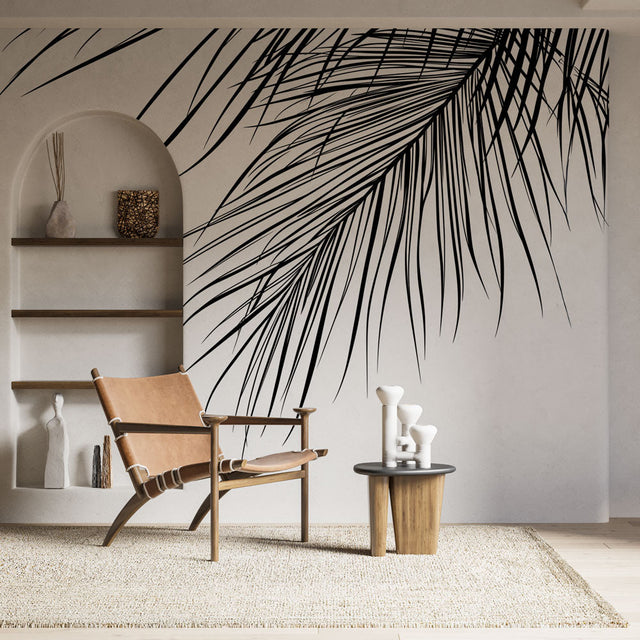 Black and white palm leaf mural wallpaper creating dramatic focal point in modern minimalist living room
