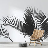 Black and white palm leaf wallpaper creating drama in a modern living room with clean furniture and natural light
