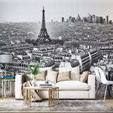 Black and white Paris cityscape wallpaper creating depth in modern living room with gray sofa and minimal decor