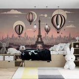 Paris Hot Air Balloon wallpaper creates a magical atmosphere in a girl's bedroom, with soft pink sunset tones