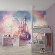 Princess castle wallpaper in a bright girl's bedroom showing pink and gold design above white furniture