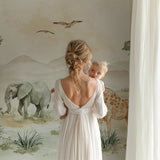 Gentle safari mural adding warmth to baby room with wooden furniture