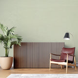 Sage green minimalist wallpaper in a bright Scandinavian living room showing natural light interaction