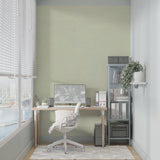 Home office space with sage green minimalist wallpaper creating a focused environment