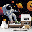Space adventure wallpaper creates cosmic dreams in a modern kids bedroom, with happy planets and floating astronaut design