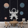 Space themed wallpaper with swinging astronaut brings wonder to a modern kids bedroom, perfect for dreamy bedtime stories