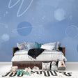 Space mural wallpaper creating cosmic atmosphere in modern kids bedroom with blue galaxy and planets design