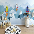 Space themed wallpaper with rockets and mountains shown in a bright modern kids bedroom with blue accents