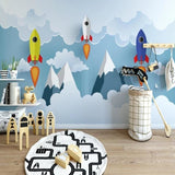 Space themed wallpaper with rockets and mountains shown in a bright modern kids bedroom with blue accents