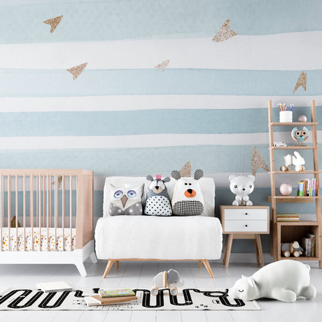 Blue and white striped nursery wallpaper with gold planes in a bright modern nursery with white furniture