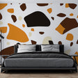 Modern Terrazzo Wallpaper with orange and brown pattern shown in a bright living room setting with minimal furniture