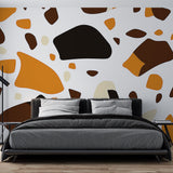 Modern Terrazzo Wallpaper with orange and brown pattern shown in a bright living room setting with minimal furniture