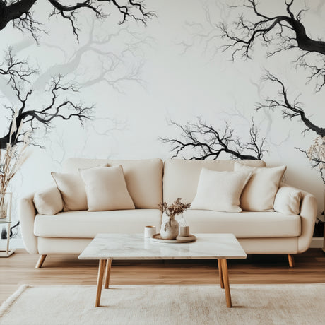 Black tree branch wallpaper creating depth in modern living room with grey sofa and natural light