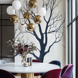 Minimalist black tree branch wallpaper creating drama in a modern living room with high ceilings