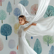 Watercolor forest wallpaper in bright nursery with white furniture, showing soft pastel trees