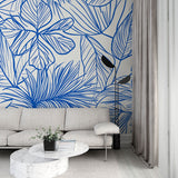 Blue tropical line art wallpaper in a bright modern living room, showing the pattern's clean aesthetic and room-expanding effect