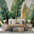 Tropical leaf wallpaper with gold accents creating a luxurious atmosphere in a modern living room with natural light