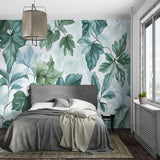 Sage green tropical leaf mural bringing nature into a calm bedroom setting