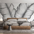 Black and white tropical leaf wallpaper creating a striking feature wall in a modern living room with minimal furniture