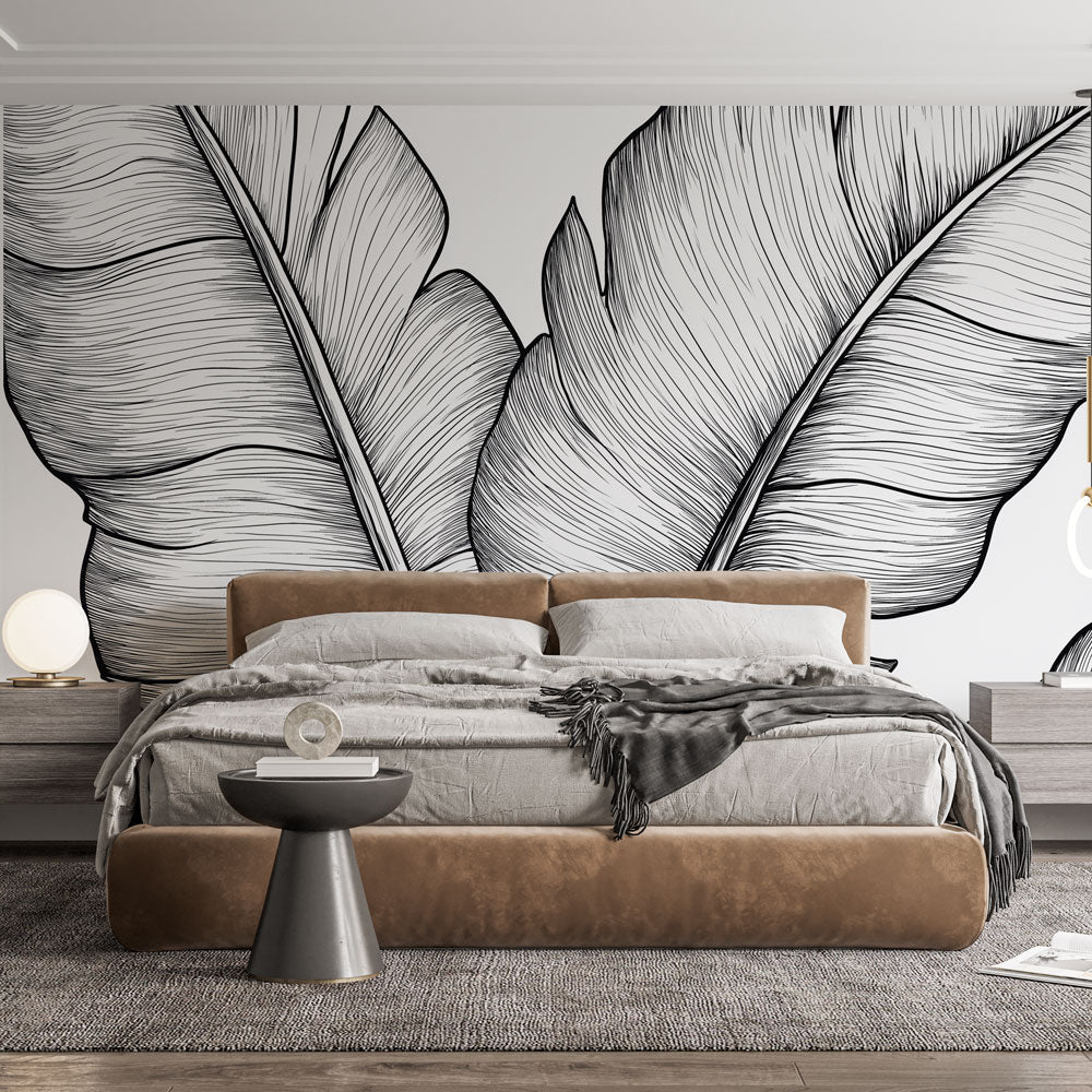 Black and white tropical leaf wallpaper creating a striking feature wall in a modern living room with minimal furniture