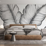 Black and white tropical leaf wallpaper creating a striking feature wall in a modern living room with minimal furniture