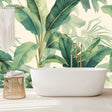 Tropical banana leaf wallpaper creating a fresh green accent wall in a bright modern living room with white sofa