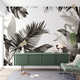 Black and white Monstera leaf wallpaper creating a dramatic statement wall in a modern living room with natural light