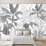 Black and white Monstera leaf wallpaper in a bright modern living room with minimal furniture and natural light