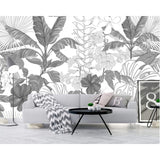 Monochrome tropical wallpaper creating depth in a stylish home office with wooden desk and white accents