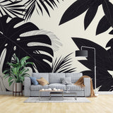 Modern living room with Black and White Tropical Monstera Leaf Wallpaper creating dramatic accent wall against minimal furniture