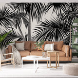 Black and white tropical palm leaf wallpaper creating dramatic impact in a modern living room with high ceilings