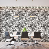 Black and white tropical palm leaf wallpaper creating a modern statement wall in a bright living room setting
