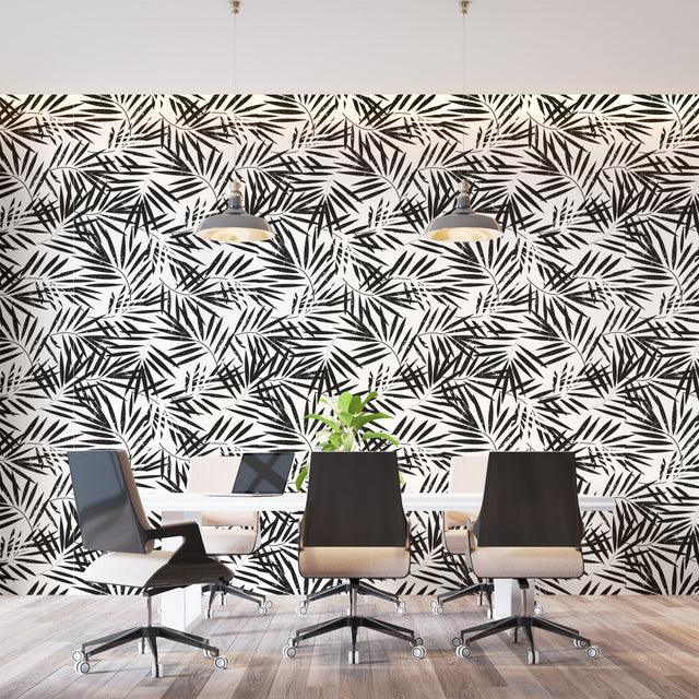Black and white tropical palm leaf wallpaper creating a modern statement wall in a bright living room setting