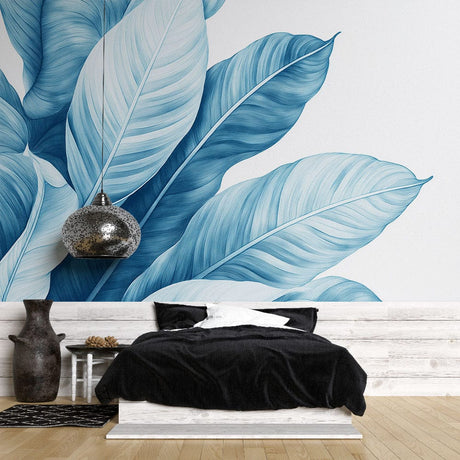 Blue Monstera leaf wallpaper creating a calm backdrop in a modern living room with white furniture and natural light