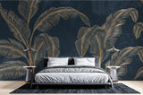 Tropical gold banana leaf wallpaper creating a stunning accent wall in a modern living room with navy and gold decor