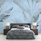 Tropical palm leaf wallpaper in blue tones creating a serene atmosphere in a modern living room with natural light