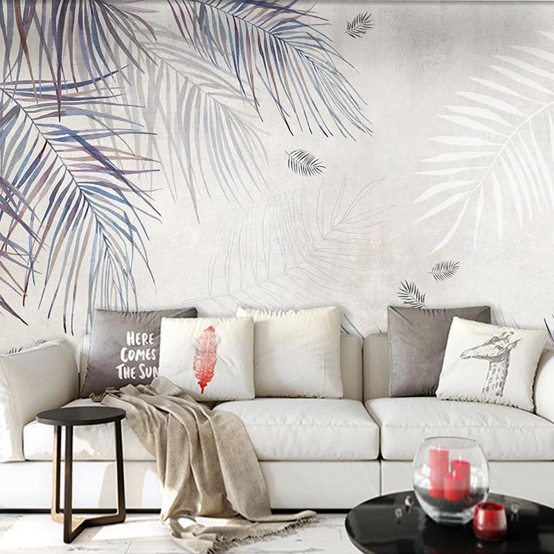 Tropical palm leaf wallpaper in modern living room showing watercolor style fronds in blue-grey tones